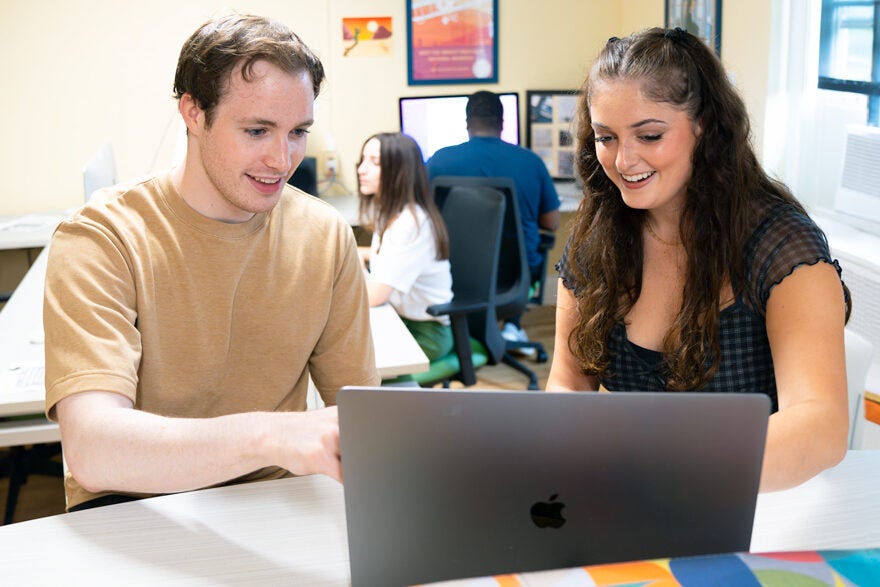 two students working together on a laptop