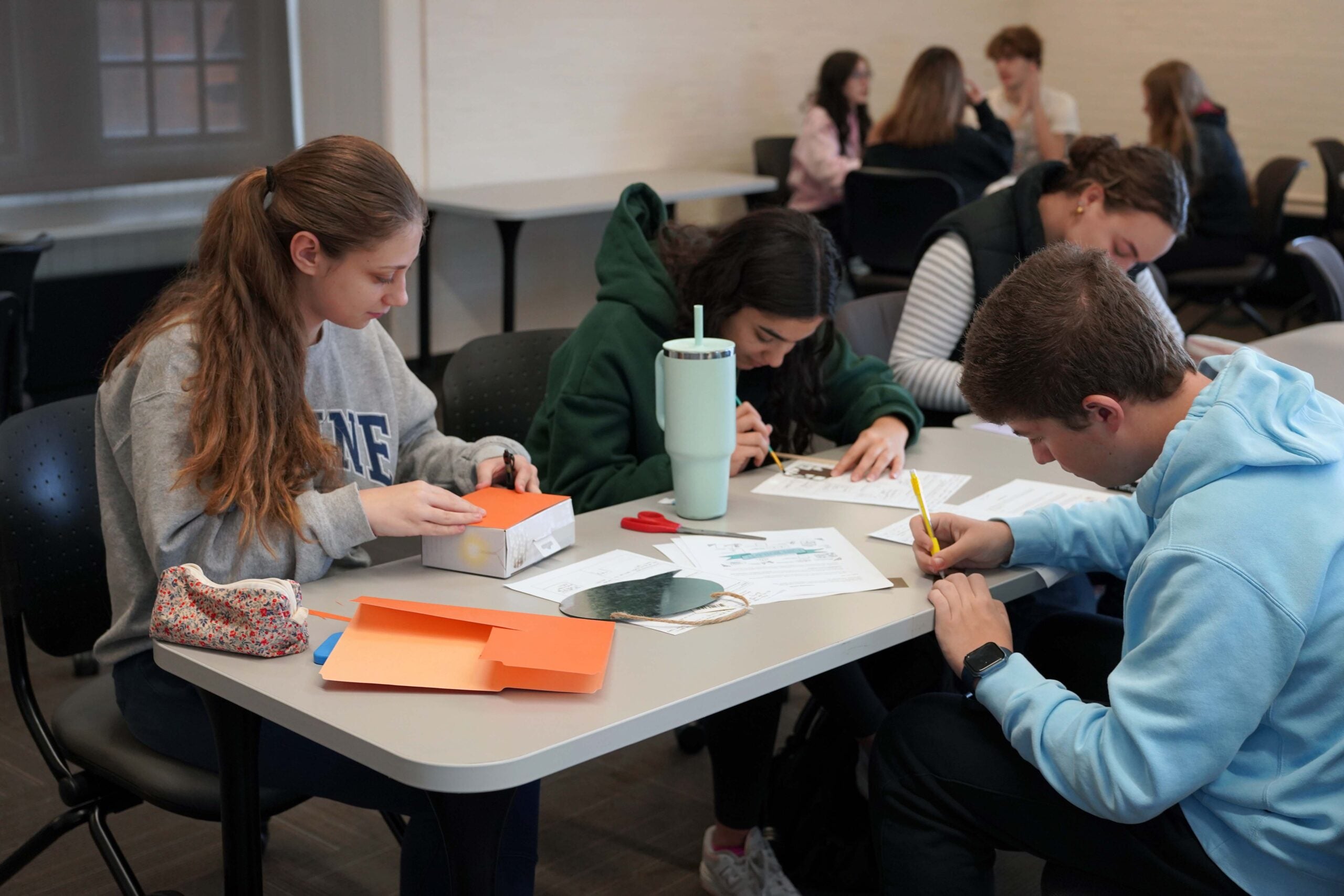 three students working together at a table.