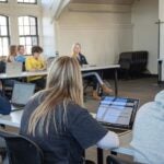 Cynthia Taylor leads a discussion in front of a classroom of students in HPR124