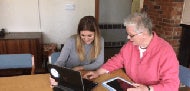 student working with older adult on a laptop