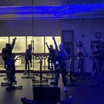 a group of students in the cycle studio with the lights off