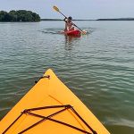 kayaking on lake, picture taken from a yellow kayak with guy paddeling toward camera