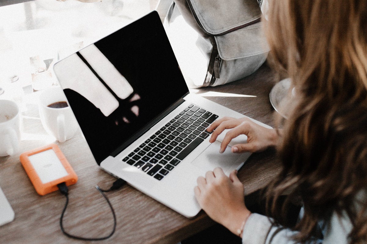 A student using a laptop next to their backpack
