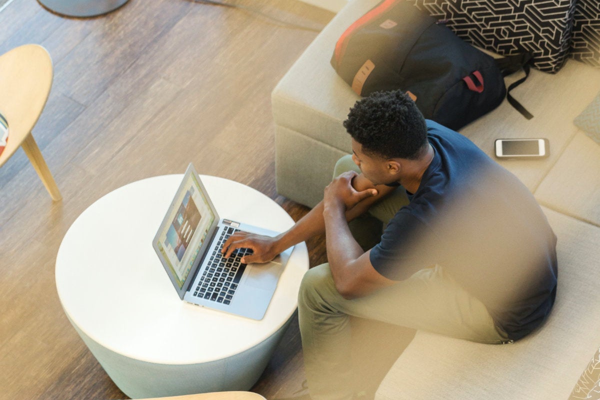A student viewed from above in a public space with contemporary furnishings working on a computer, photo LinkedIn Sales Navigator from Unsplash