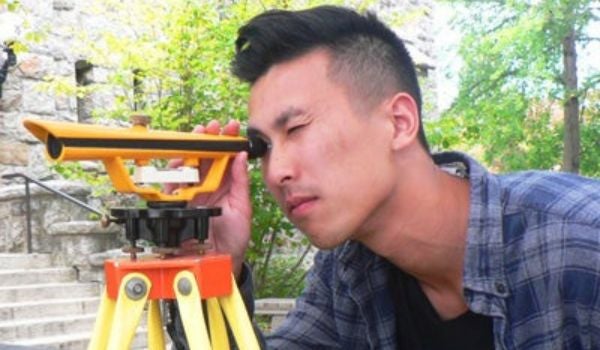 a student looking through a scope for surveying