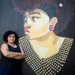 Angela Gonzalez standing in front of her artwork in Providence