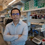 professor yang lin poses with arms across chest in his lab