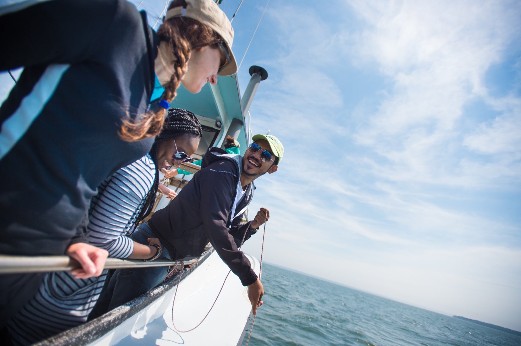 Three people on the side of a boat, smiling