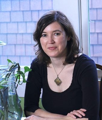 photo of white woman, seated indoors, smiling, named Madeline Ostrander