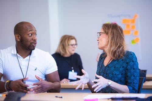 A Black man and a white woman are deeply engaged in conversation