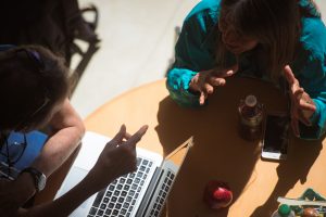 Photo of people at table gesturing with their hands.