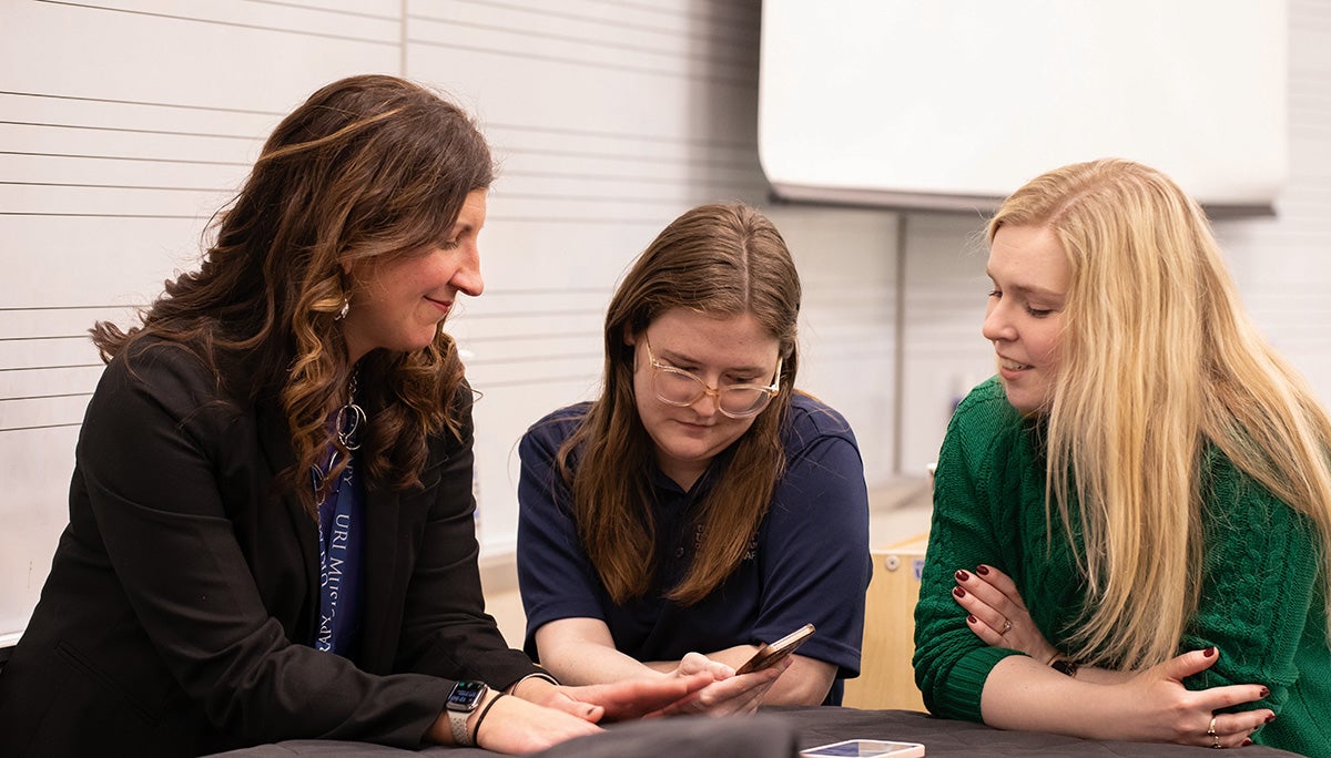 O'Malley (right) reads a cell phone message with two students