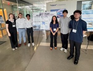 Six young people stand in front of a scientific research poster.