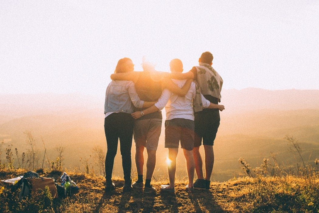 Image of four people embracing outdoors at sunrise