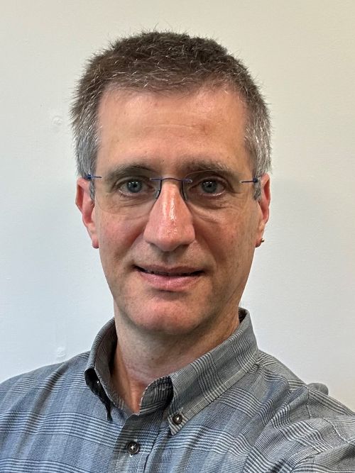 Brian Mitchell, wearing a blue button-down shirt, smiling.