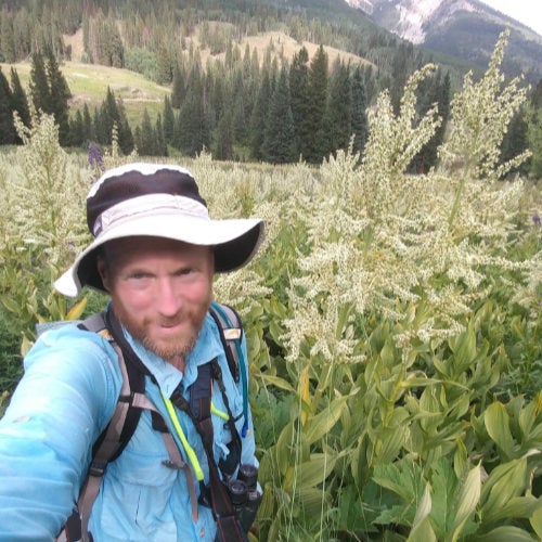 Natural Resources Science faculty member, Chris Floyd in a field with mountains in the background