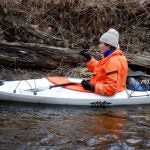 URI graduate student John Crockett examines chewed sticks while conducting a survey for muskrats, beavers and river otters in western Rhode Island.