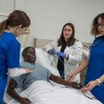 URI College of Nursing Clinical Assistant Professor Ashlee Sackett works with nursing students in one of the college's advanced simulation labs. Sackett has earned international certification in nursing simulation education.