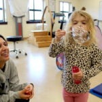 URI Nursing student Marisha Anand plays with Ava, 4, as she blows bubbles during the respite care program on a recent Saturday afternoon.