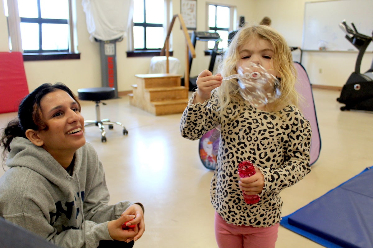 URI Nursing student Marisha Anand plays with Ava, 4, as she blows bubbles during the respite care program on a recent Saturday afternoon.