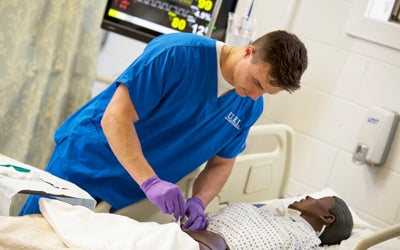 A nursing student working on a simulator