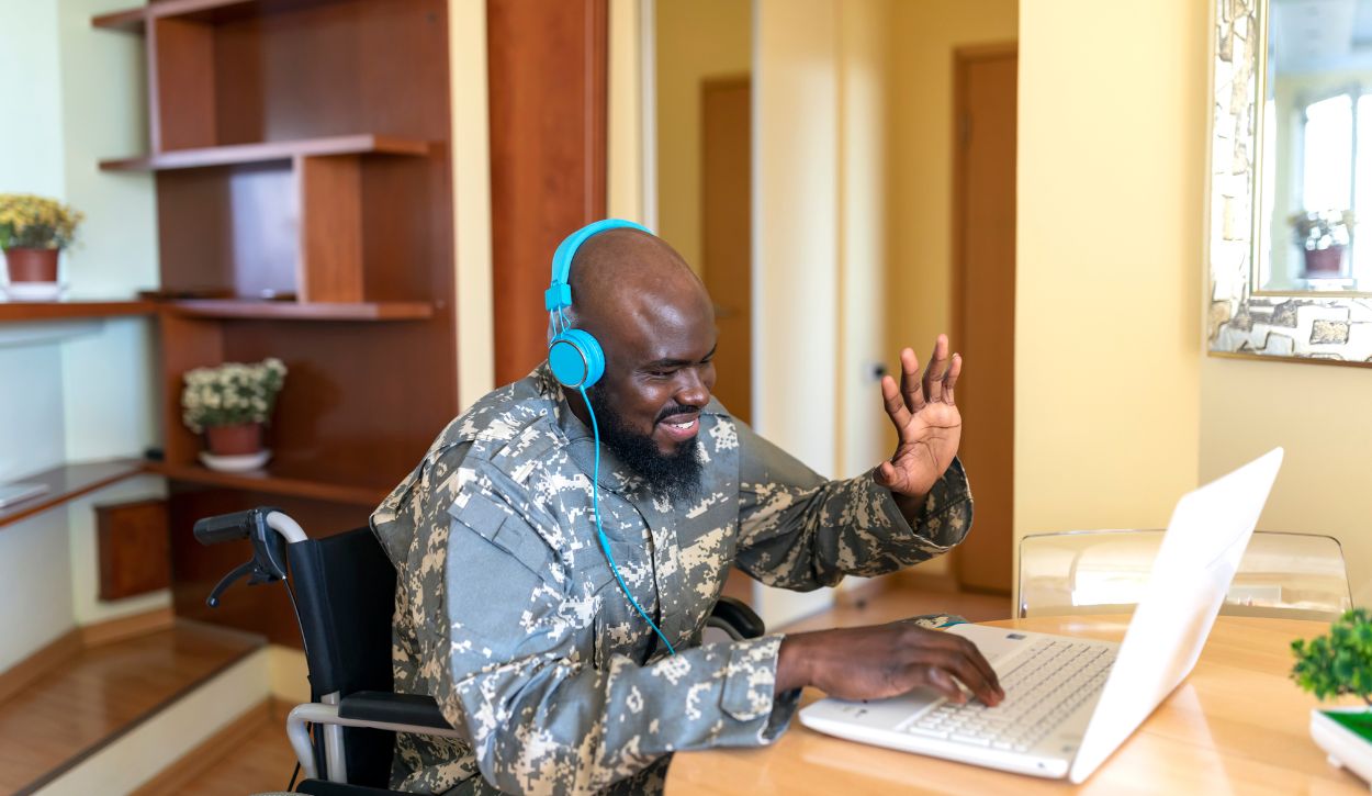 A military veteran waves at his laptop while on a virtual call.