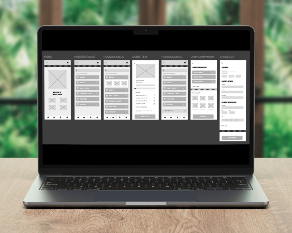 The image depicts a laptop on a wooden table. The laptop screen displays a series of wireframes for a website or mobile application. There are six vertically arranged wireframes labeled from left to right as "Home," "Home/Catalog," "Home/Catalog," "Menu Item," "Order Confirmation," and "Checkout." Each wireframe includes various design elements such as placeholders for images, text, buttons, and dropdowns. The screen is set against a softly blurred background showing green foliage and a window, creating a contrast between the digital wireframes and the natural setting outside.