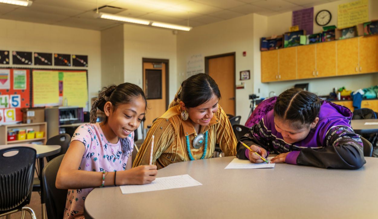 Navajo indigenous teacher helping her students with their classwork