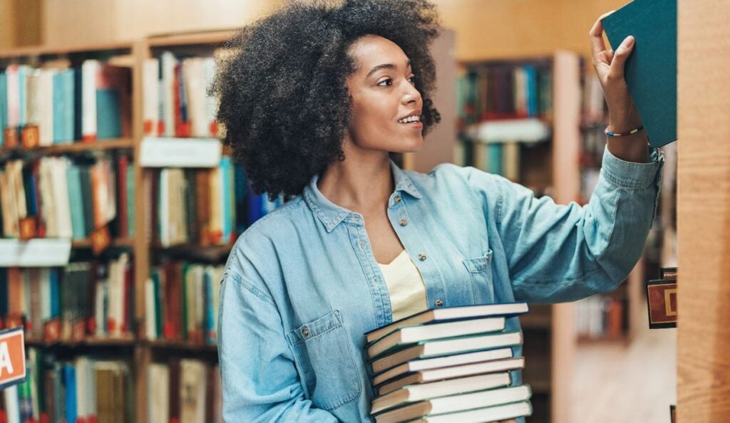 A female librarian places books back on the shelves.