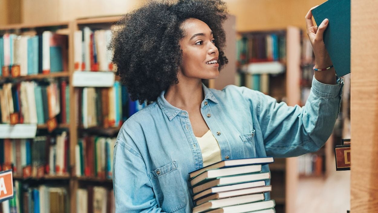 A female librarian places books back on the shelves.