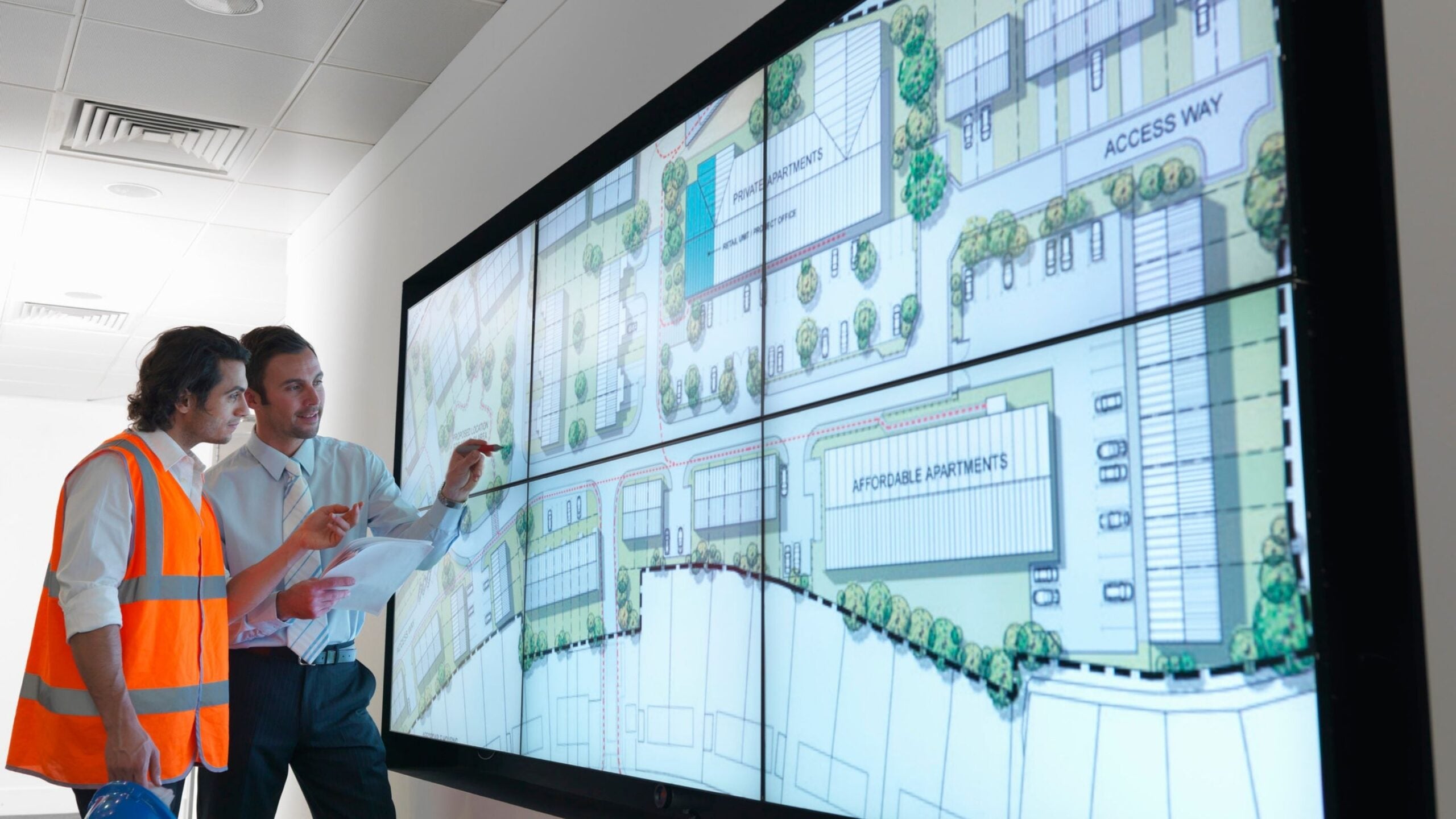 Two professionals look at a screen mapping out a municipal development