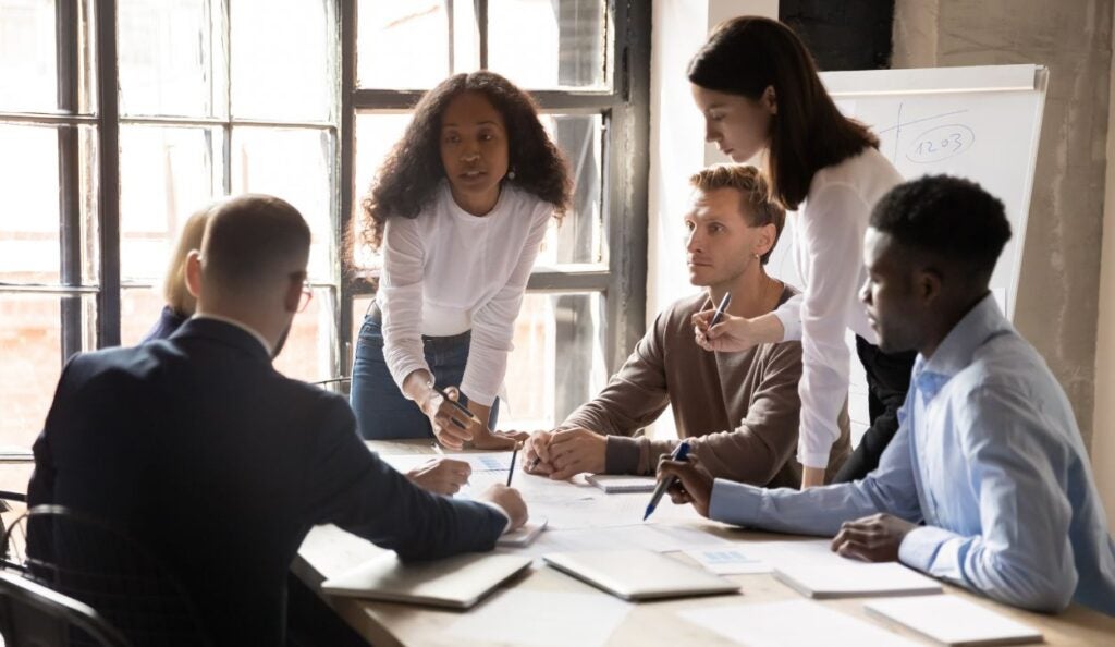 A diverse business team consults with their manager.