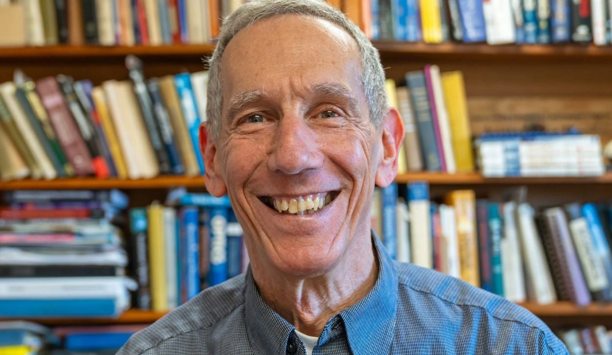 Professor Leonard Kahn smiles at the camera while sitting in his office.