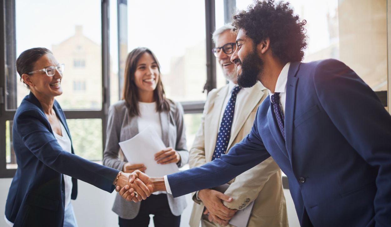 Business professionals shake hands with one another during a talent development program.