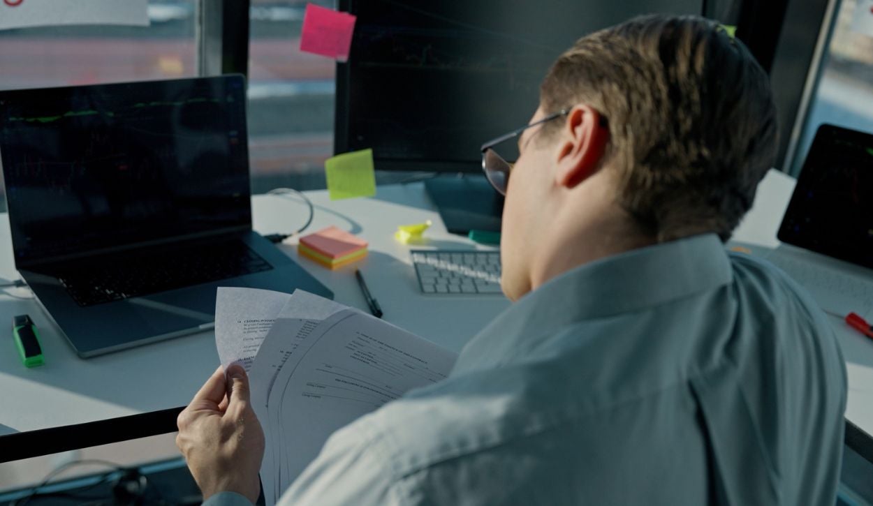 A person sitting at a desk looking at a piece of paper.