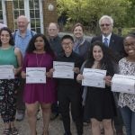 A group of students with faculty and staff mentors hold their certificates received for completing the Peace Corps Prep Program