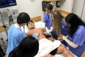 Students in South Kingstown High School's pharmacy technician program examine one of the lifelike mannequins in the URI College of Pharmacy's Simulation Laboratory during the semi-annual Exploration Day.