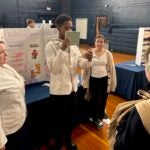URI College of Pharmacy student Shakir Spike blocks his mouth so South Kingstown High School students can't read his lips as he tests their hearing age during an interactive health and wellness fair at the High School on Dec. 5.