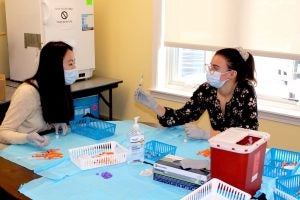 Pharmacy students Yan Cen and Melissa Gianetti prepare COVID-19 vaccinations at Westerly Senior Center, where they volunteer drawing up and administering vaccines.