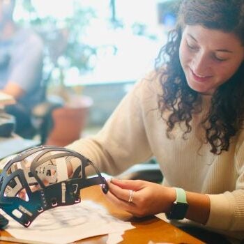 a young woman works on a helmet tigheting system prototype