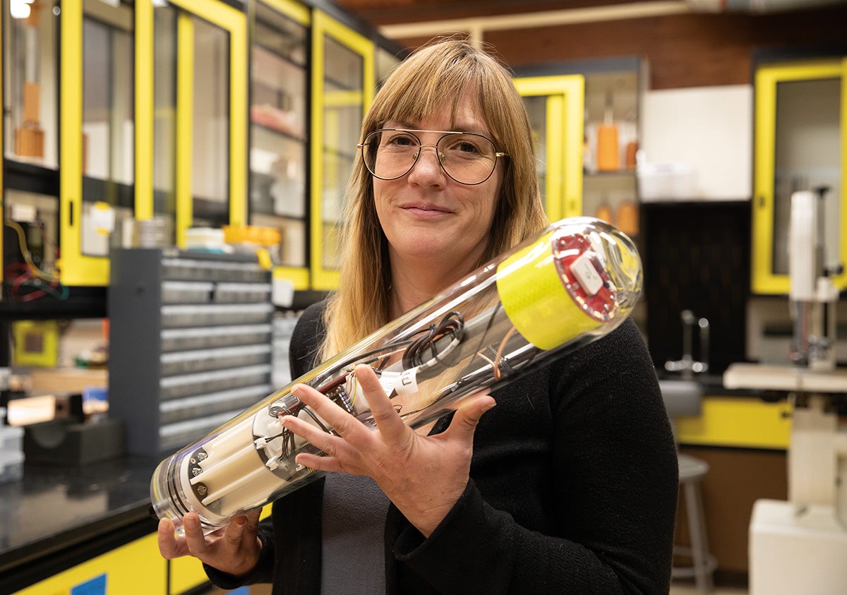 Melissa Omand holds a clear plastic tube with instrumentation inside, one of her MINION floats