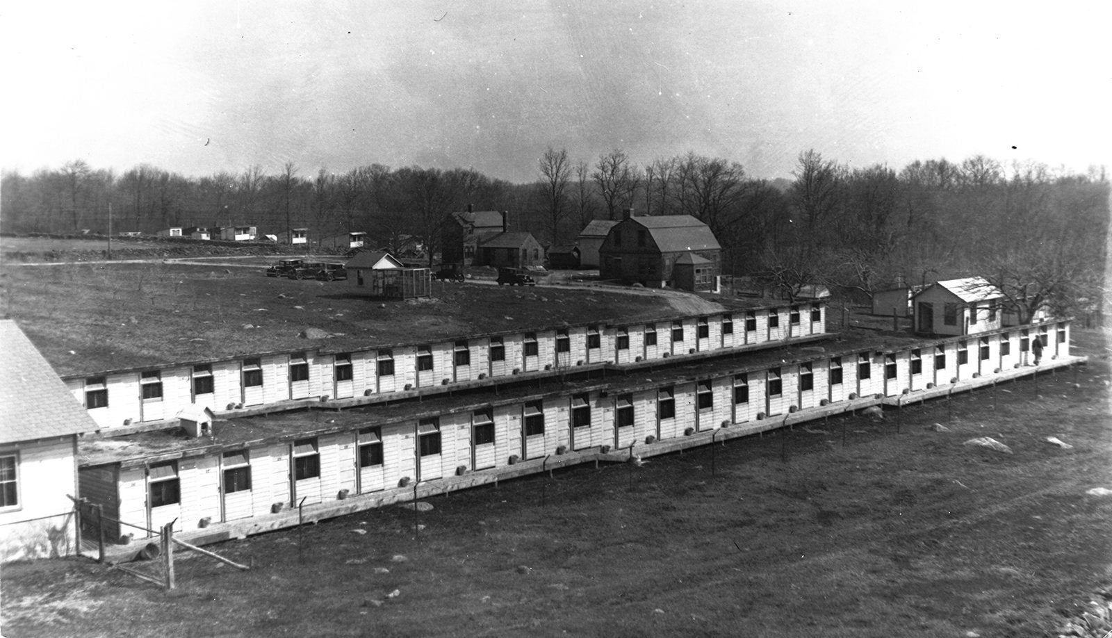A black and white image showing a long, low building with small uniform sized windows