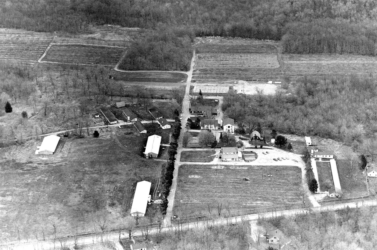 A black and white aerial photo of East Farm from 1965, showing the buildings and the cars an farming trucks of the era