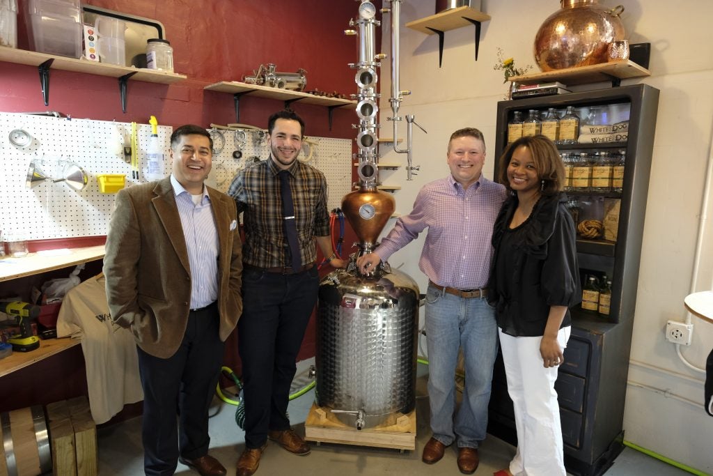 a group of business professionals stand together at White Dog Distillery