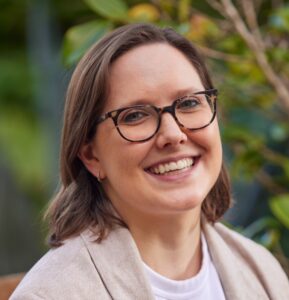 Headshot of lab member Erin Jones smiling in front of a leafy background