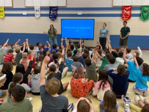 Three graduate students ask a crowd of children which ocean we live next to.