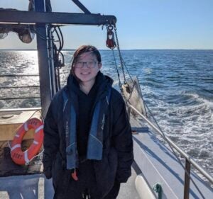 Image of a young woman standing on the deck of a ship.