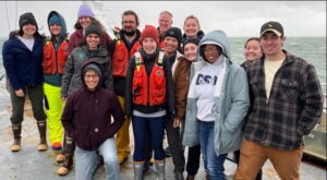 Scientists on a ocean research cruise pose for a photo on the deck of their research vessel.