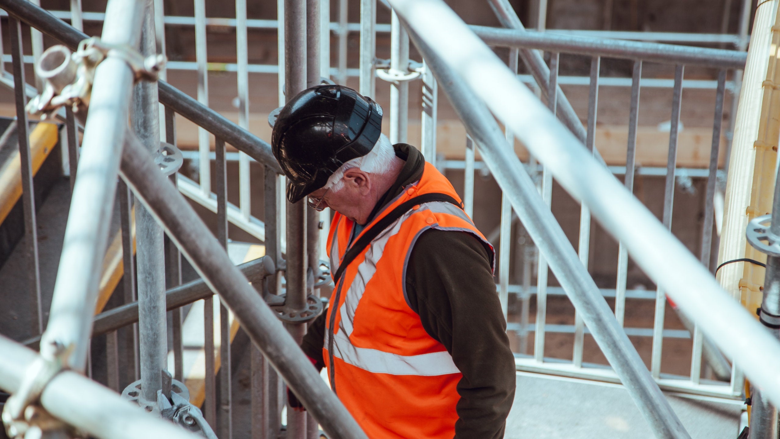 An older man wearing a safety vest at a construction site