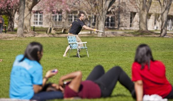 a student throws a frisbee while others watch